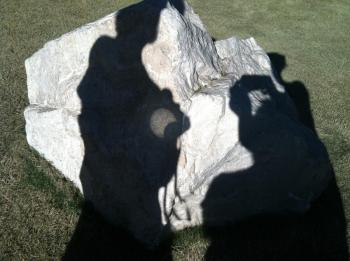 Solar eclipse projected through binoculars onto the surface of a rock